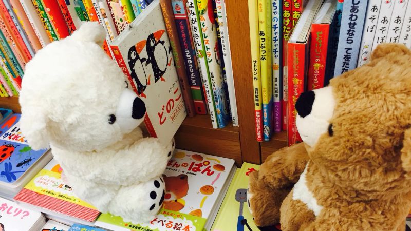 Two stuffed animals with a bunch of books