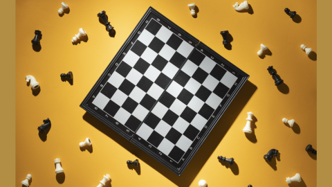 A chess board in the middle of a yellow background, chess pieces are all over the yellow background.
