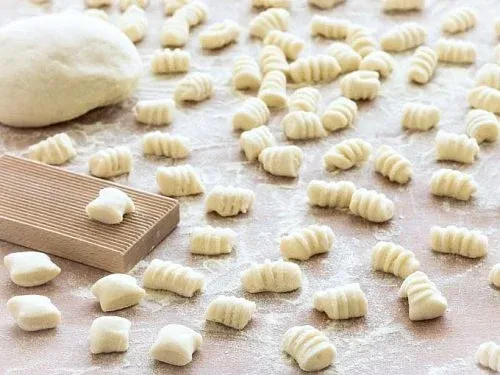 Fresh made gnocchi spread out with a bigger piece of dough on the side 