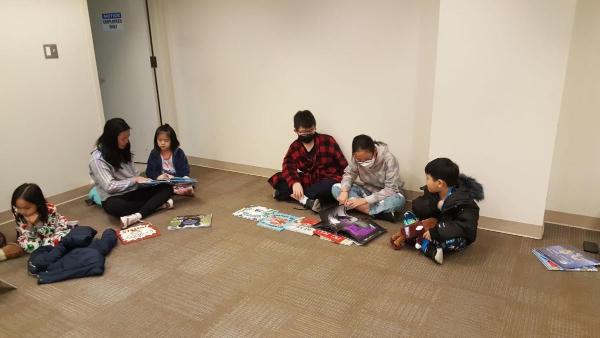 Teens and children reading picture books together